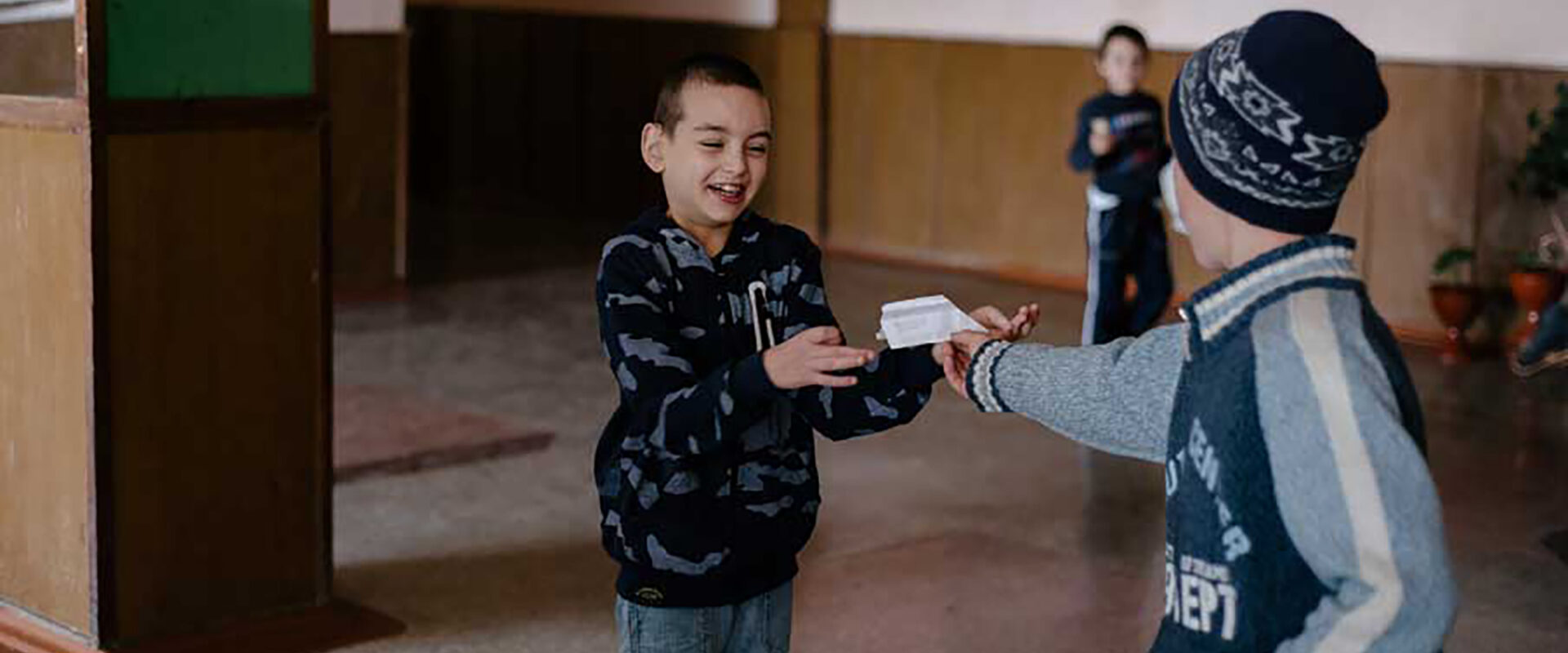 Två pojkar leker med ett pappersflyplan.