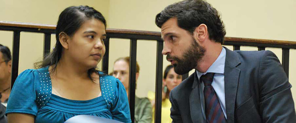 Imelda Cortez med sin advokat i rättegång. Hon pratar med sin advokat. Imelda har en blå tröja på sig.