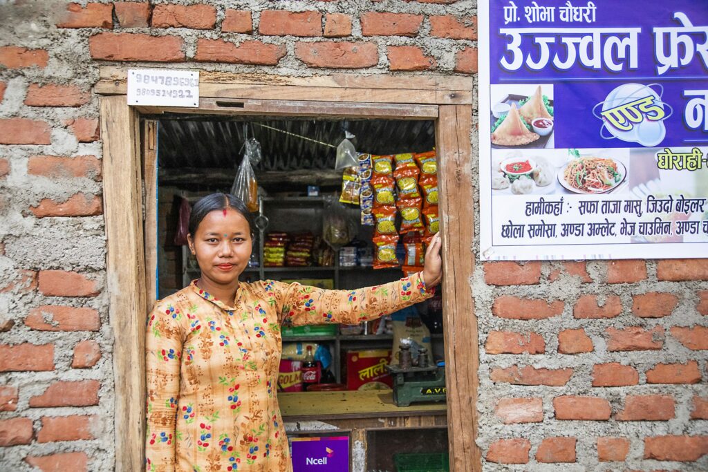 Flicka i Nepal framför en butik.
