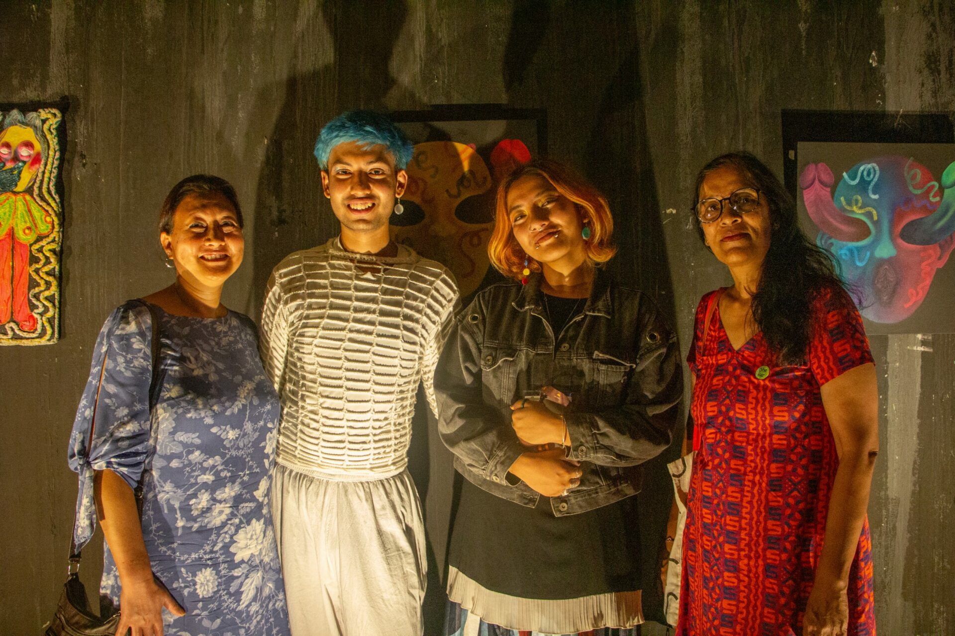 Fyra personer i förgrunden, konst på väggarna i bakgrunden.