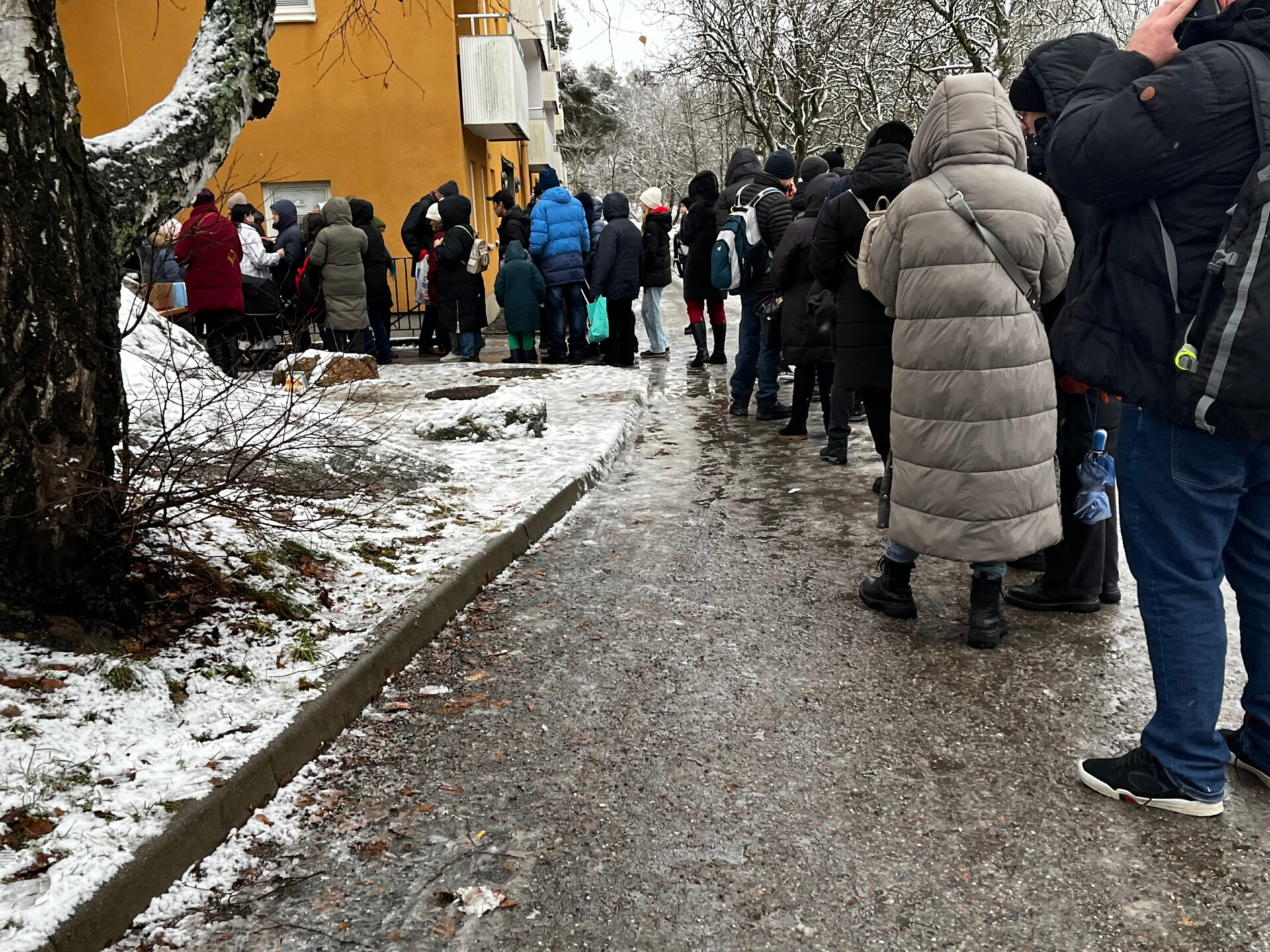 Vinterbild på folk som köar till matutdelning.